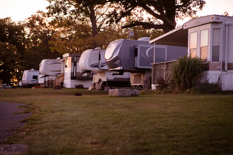 Fifth wheels and a park model along the lawn at dusk