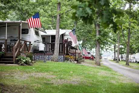 Travel trailer flying a US flag under shade trees