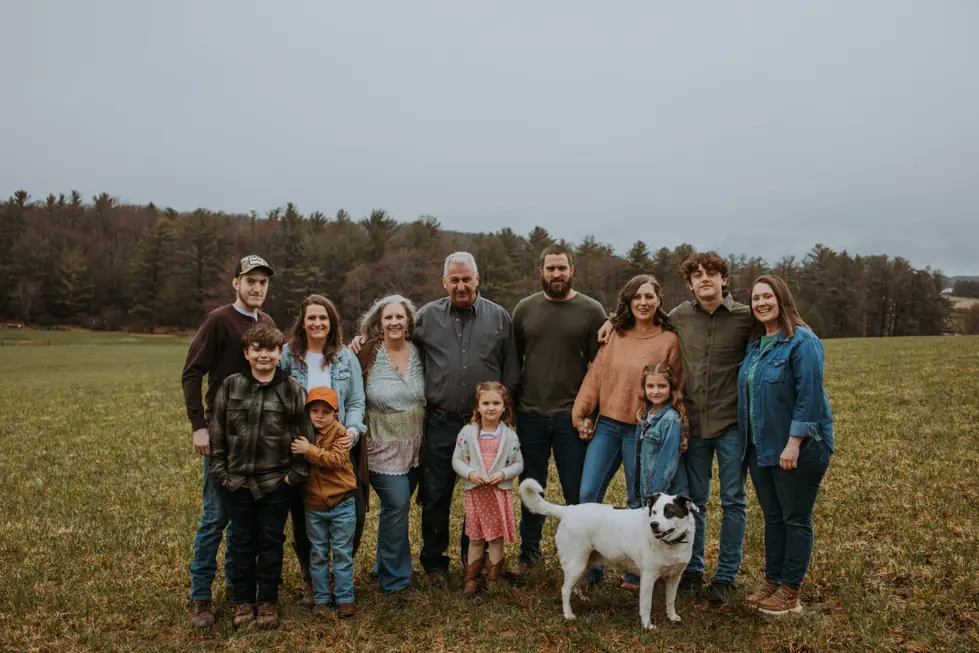 The Glotfelty family standing in a hay field with their white dog