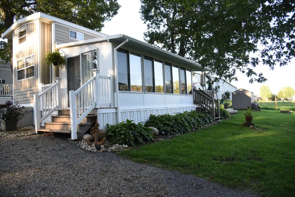 Park model with a sunroom, front porch and flower beds