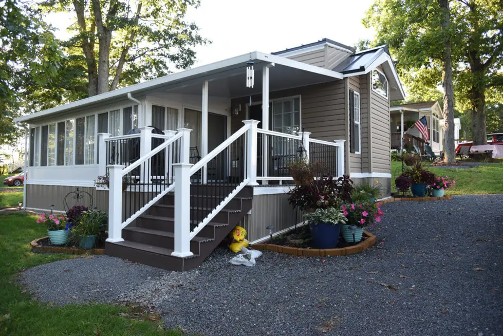 Park model with a white porch rail and gravel drive