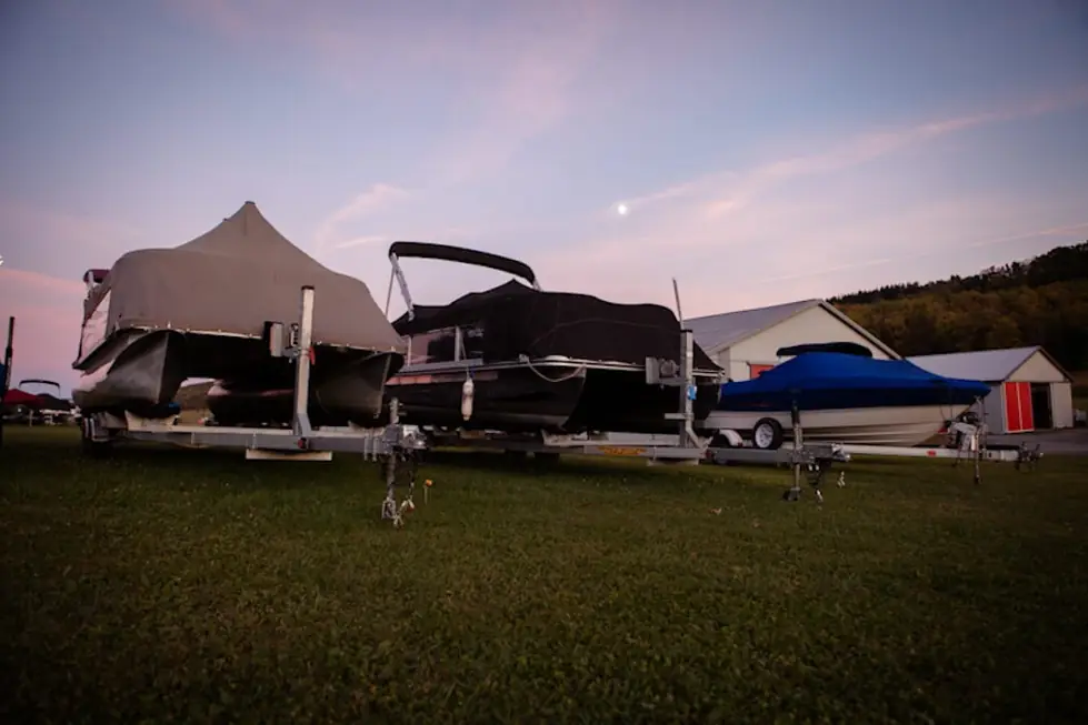 Covered boats on trailers lined up in the D&W Storage yard at dusk